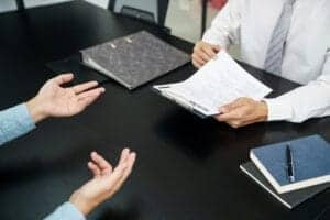 HR Consultant holding papers across a desk to a client