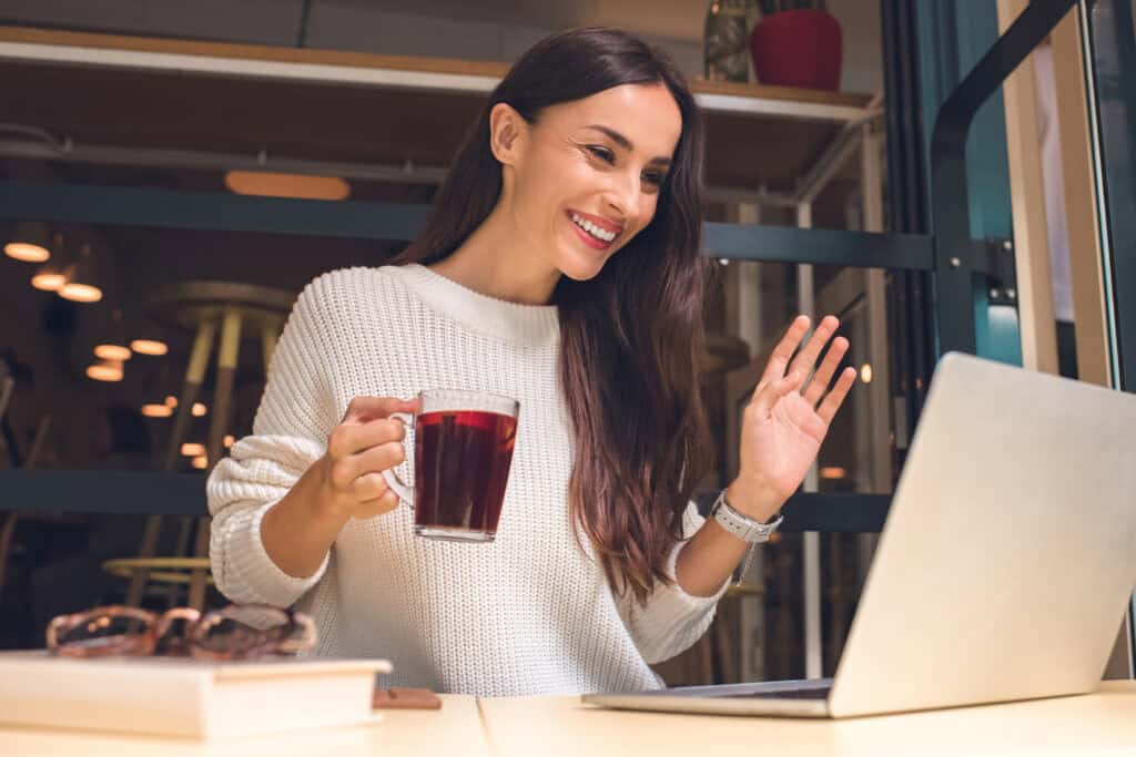 woman on a video call with a cup of coffee or tea on a virtual coffee break