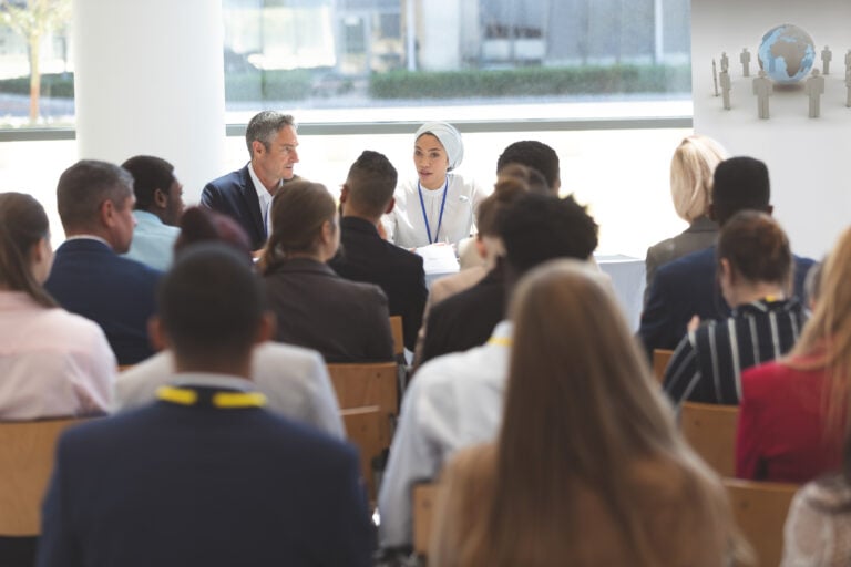 Rear view of group of diverse business people attending a business seminar in office building