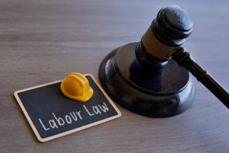 Judge’s gavel beside a yellow construction hard hat on a chalkboard labeled labour law