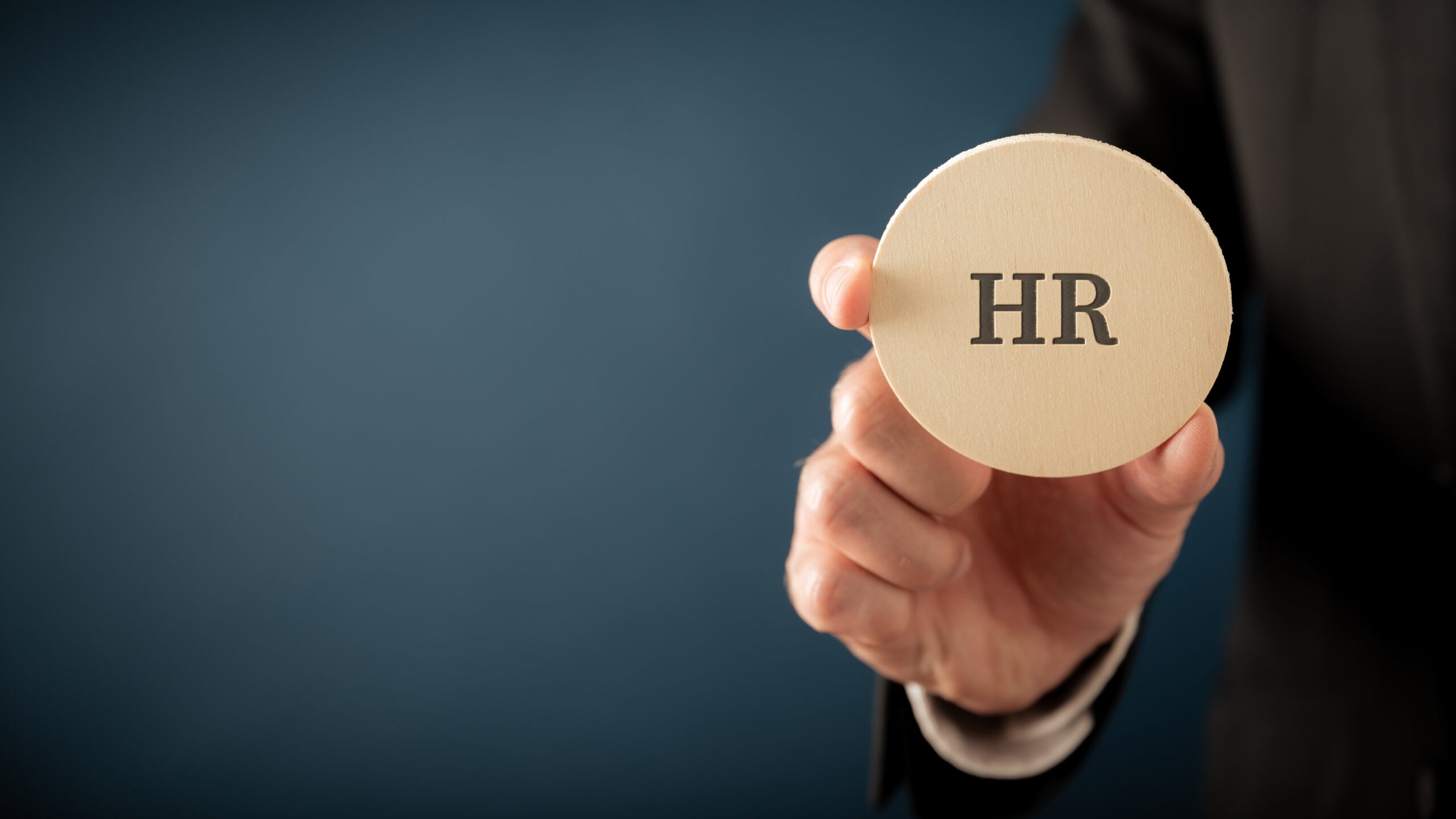 Business executive holding a wooden HR token, representing fractional CHRO leadership and human resources strategy