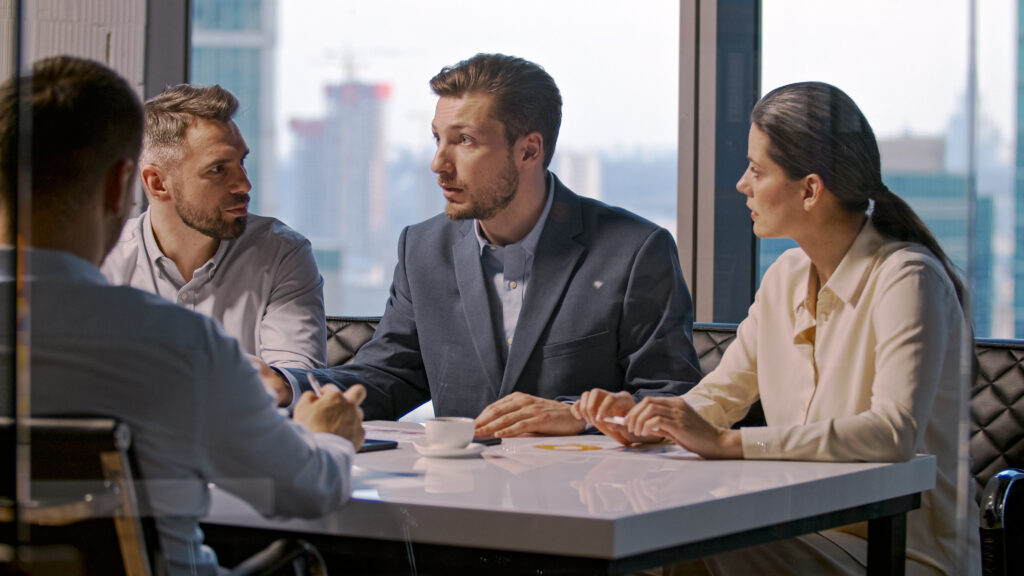 A small executive team engaged in a strategic discussion at a conference table, representing the kind of leadership advisory work a fractional CHRO provides.