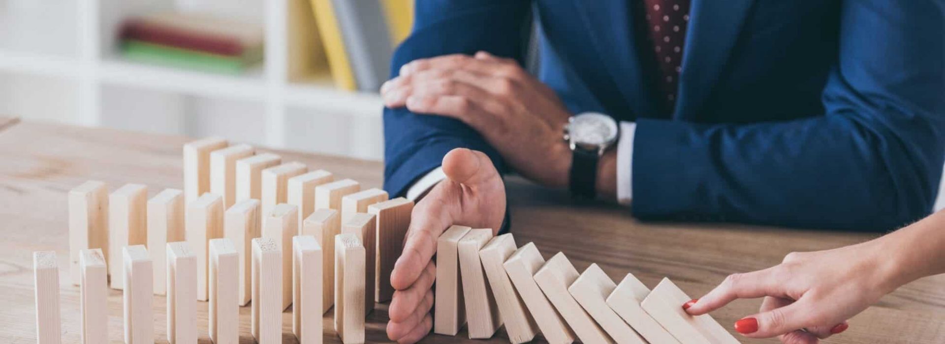 cropped view of woman pushing wooden block and risk manager stopping domino effect