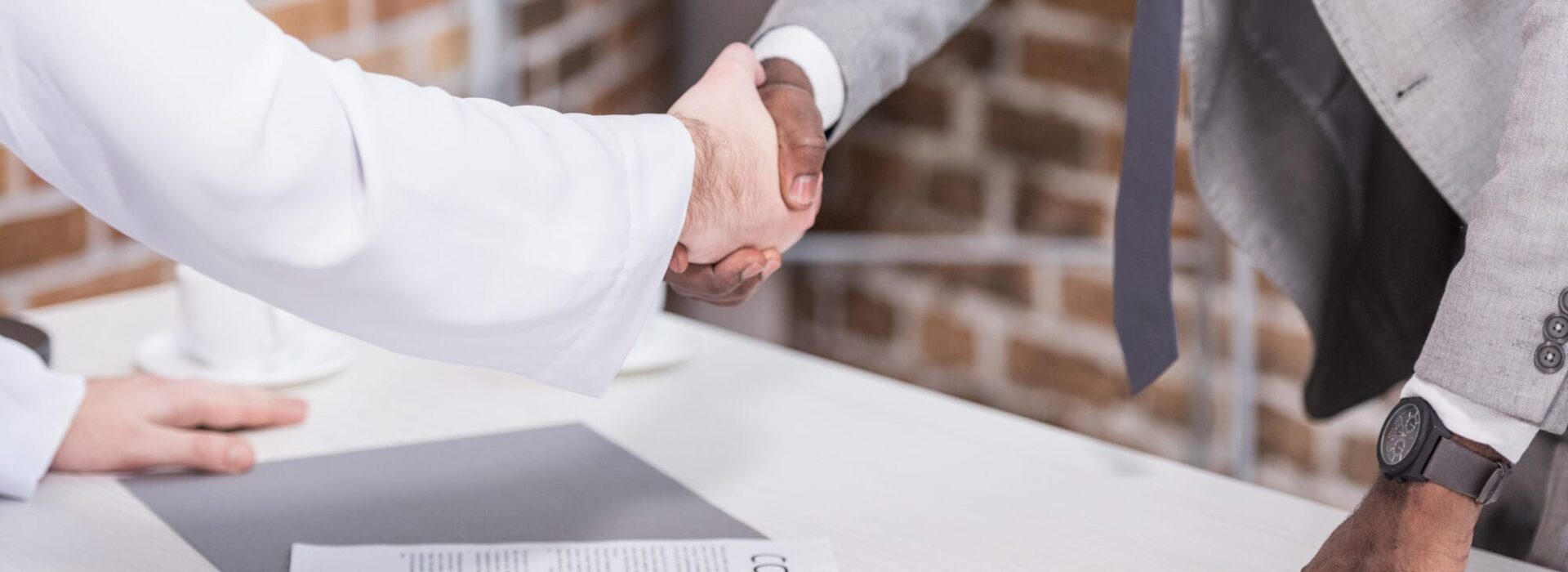 Multiethnic businessmen shaking hands before signing a non-compete agreement in office